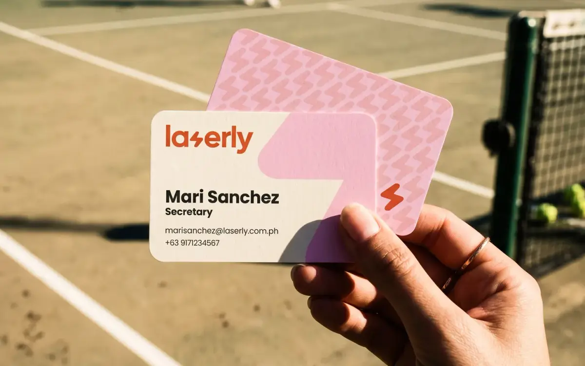 Laserly business cards held up on a tennis court