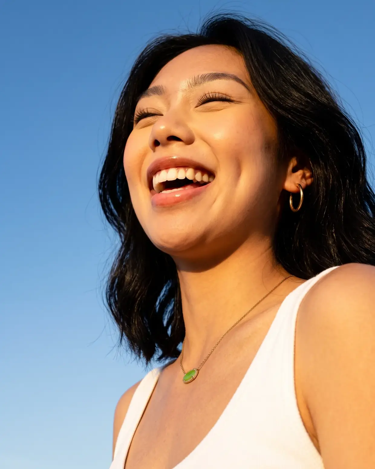 Smiling woman with Laserly treatment-area icons pointing to her face and shoulders